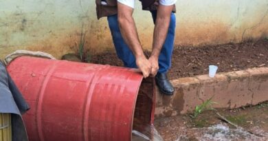 agente de endemias virando tambor com água possível foco de dengue