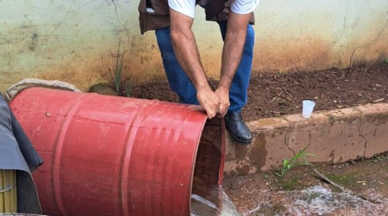 agente de endemias virando tambor com água possível foco de dengue