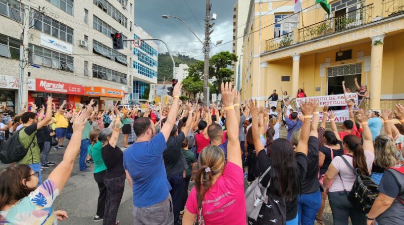 servidores municipais fazendo protestos com os braços levantados