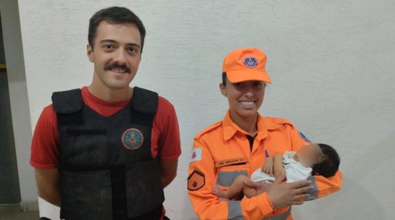 bebê de 7 dias no colo da bombeiro militar de Alfenas-MG após o salvamento. O recém nascido havia se engasgado.