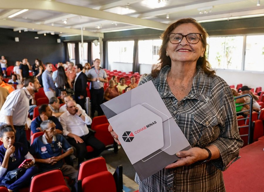 mulher recebendo escritura da cohab mg