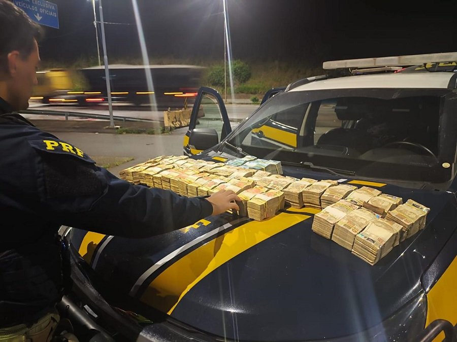 agente da policia rodoviária federal contando quase 1 milhão de reais apreendido durante fiscalização