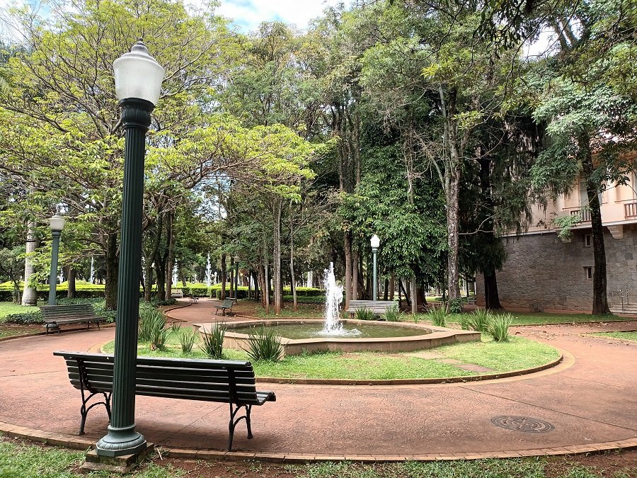 um poste dois bancos e uma fonte no parque José Affonso Junqueria em Poços de Caldas