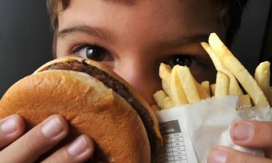 adolescente com hamburguer e batata frita